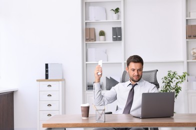 Photo of Man using remote to control air conditioner in office