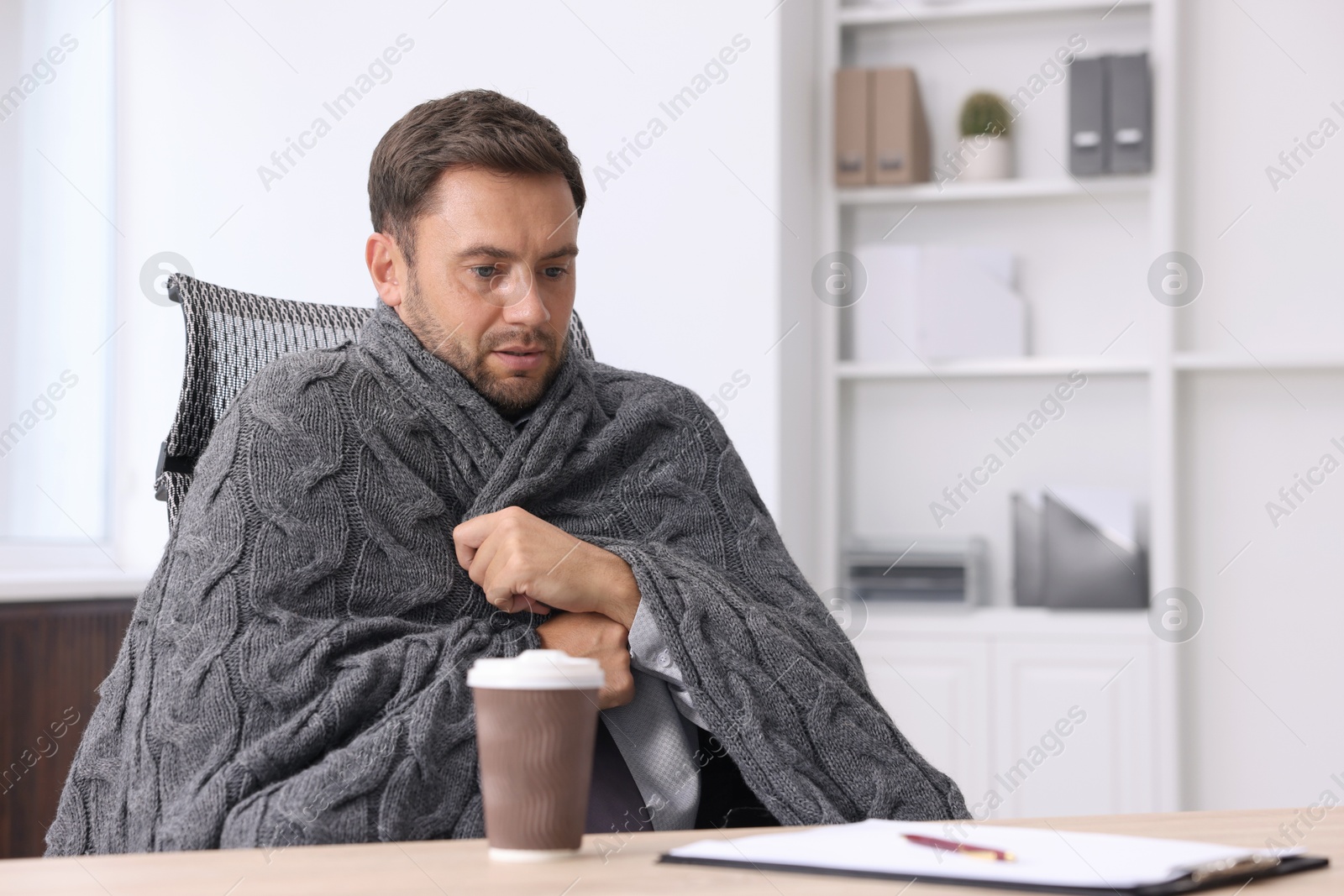 Photo of Air conditioning. Man with blanket suffering from cold temperature at workplace in office