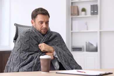 Photo of Air conditioning. Man with blanket suffering from cold temperature at workplace in office