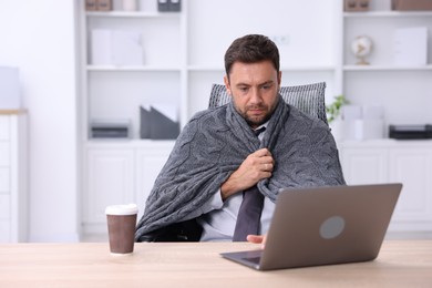 Photo of Air conditioning. Man with blanket suffering from cold temperature at workplace in office