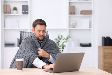 Photo of Air conditioning. Man with blanket suffering from cold temperature at workplace in office