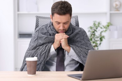 Photo of Air conditioning. Man with blanket suffering from cold temperature at workplace in office