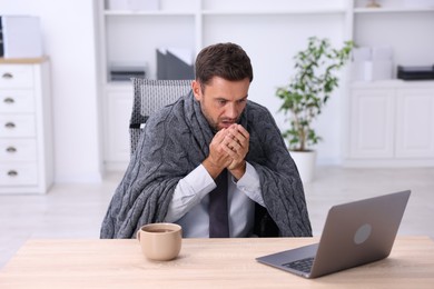 Photo of Air conditioning. Man with blanket suffering from cold temperature at workplace in office