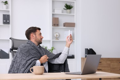Photo of Man using remote to control air conditioner in office