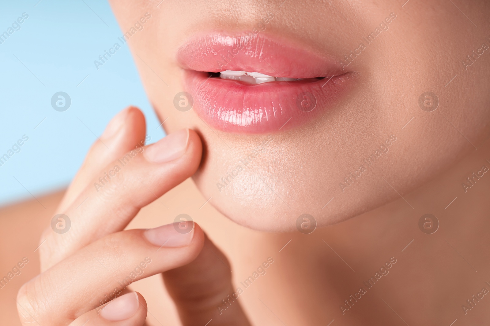 Photo of Woman with beautiful lips on light blue background, macro view
