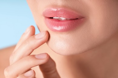 Photo of Woman with beautiful lips on light blue background, macro view