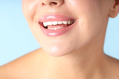 Photo of Woman with beautiful lips on light blue background, macro view