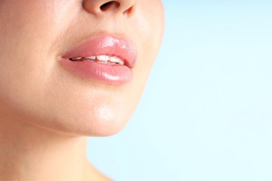 Photo of Woman with beautiful lips on light blue background, macro view. Space for text