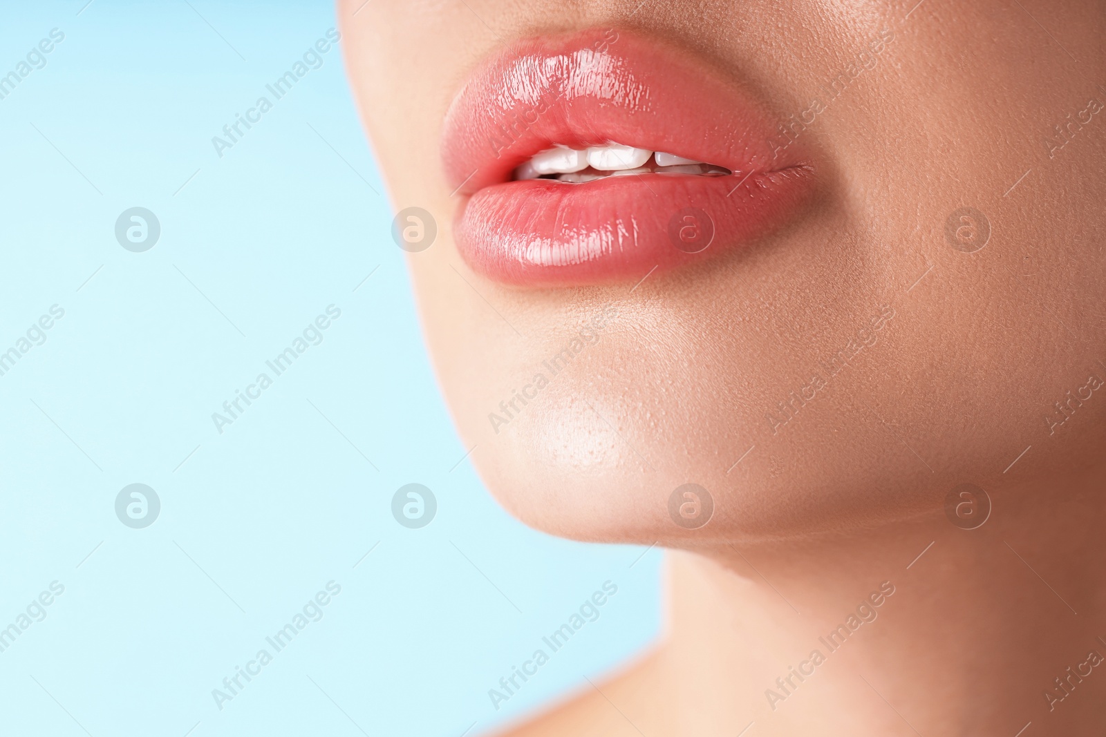 Photo of Woman with beautiful lips on light blue background, macro view. Space for text