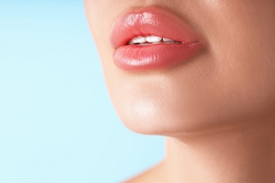 Photo of Woman with beautiful lips on light blue background, macro view. Space for text