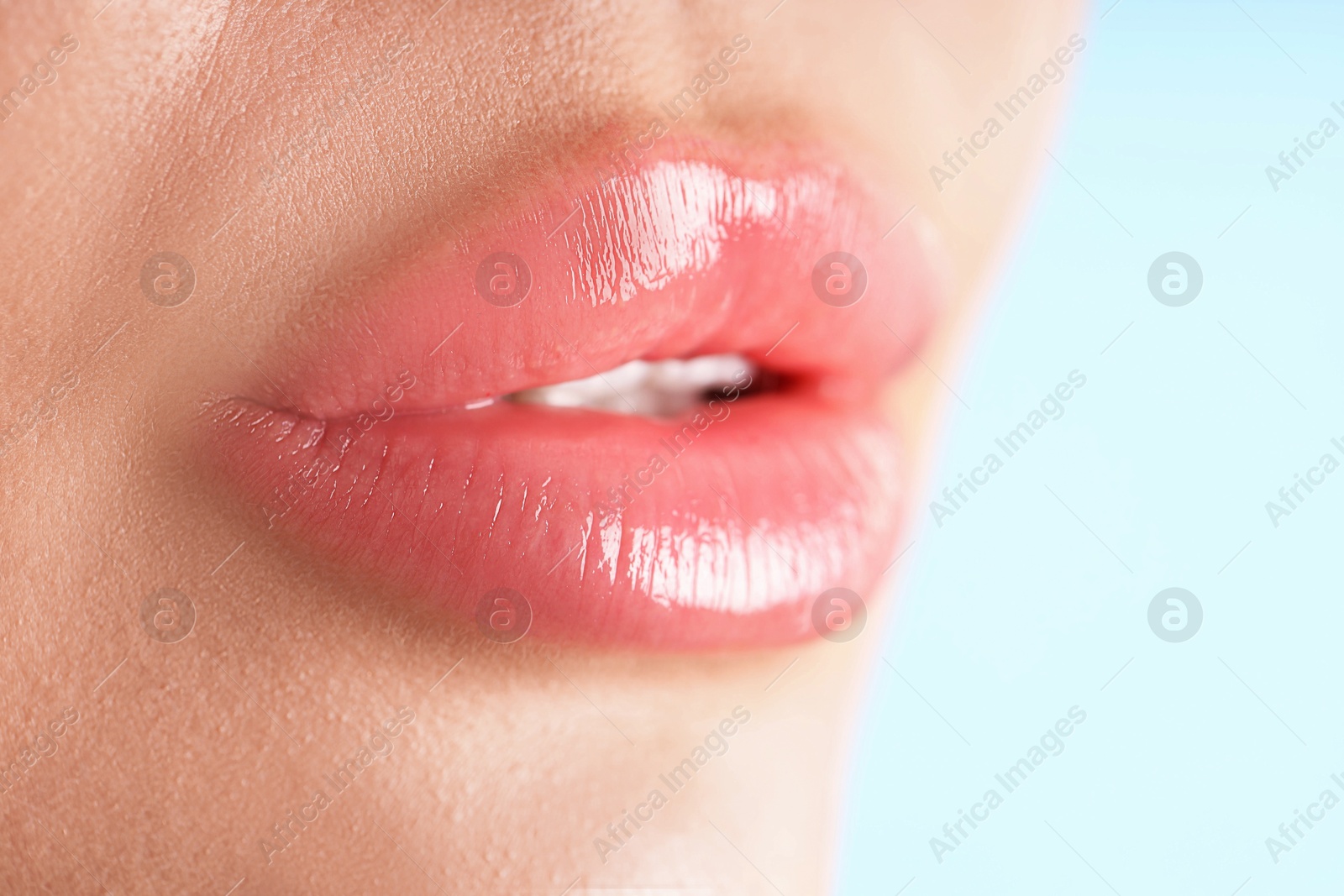 Photo of Woman with beautiful lips on light blue background, macro view