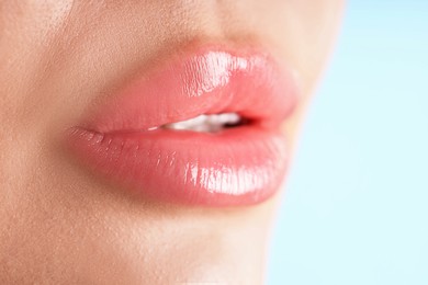Photo of Woman with beautiful lips on light blue background, macro view