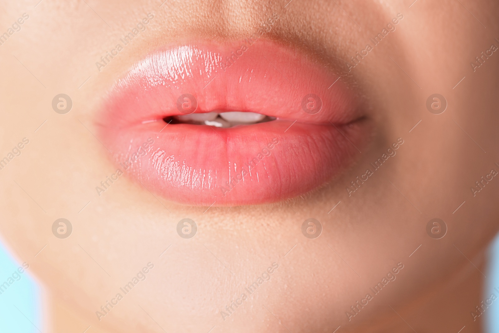 Photo of Woman with beautiful lips on light blue background, macro view