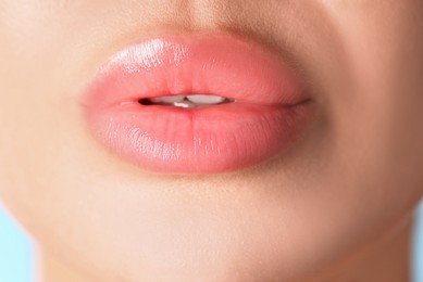 Photo of Woman with beautiful lips on light blue background, macro view