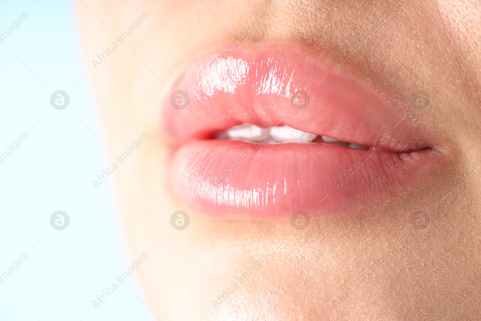 Photo of Woman with beautiful lips on light blue background, macro view