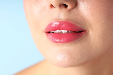Photo of Woman with beautiful pink lipstick on her lips against light blue background, macro view