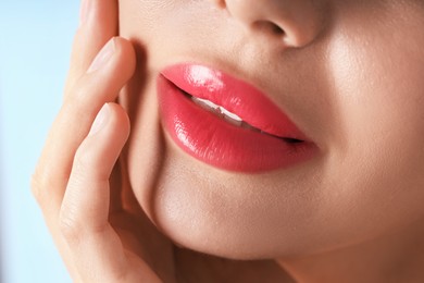 Photo of Woman with beautiful pink lipstick on her lips against light blue background, macro view