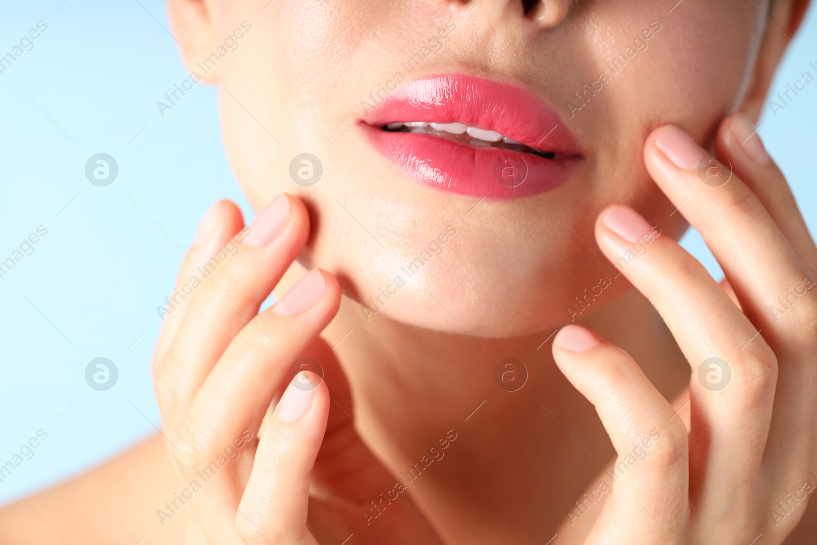Photo of Woman with beautiful pink lipstick on her lips against light blue background, macro view