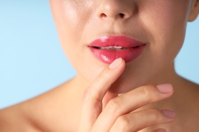 Photo of Woman with beautiful pink lipstick on her lips against light blue background, macro view