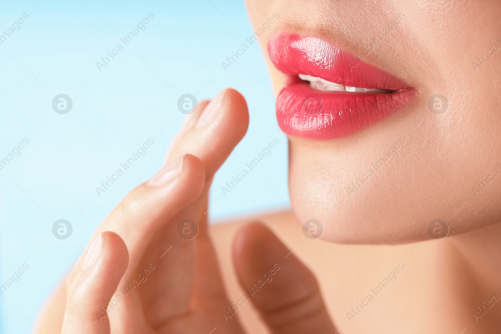 Photo of Woman with beautiful pink lipstick on her lips against light blue background, macro view