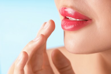 Photo of Woman with beautiful pink lipstick on her lips against light blue background, macro view