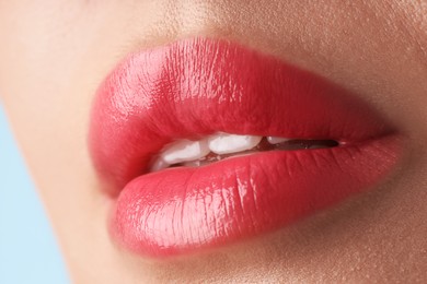 Photo of Woman with beautiful lipstick on her lips against light blue background, macro view