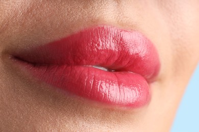 Photo of Woman with beautiful lipstick on her lips against light blue background, macro view