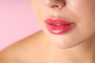 Photo of Woman with beautiful lipstick on her lips against pink background, macro view