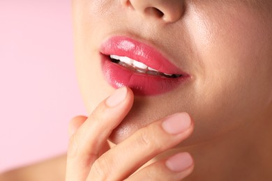 Photo of Woman with beautiful lipstick on her lips against pink background, macro view