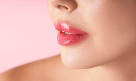 Photo of Woman with beautiful lipstick on her lips against pink background, macro view