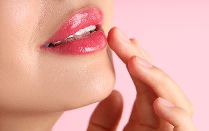 Photo of Woman with beautiful lipstick on her lips against pink background, macro view