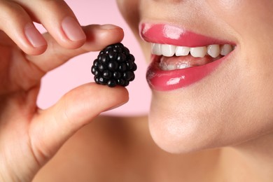 Photo of Woman with beautiful lipstick on her lips and blackberry against pink background, macro view