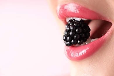 Photo of Woman with beautiful lipstick on her lips and blackberry against pink background, macro view. Space for text