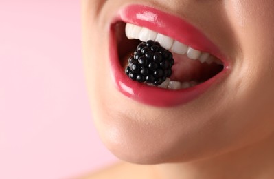 Photo of Woman with beautiful lipstick on her lips and blackberry against pink background, macro view