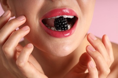 Photo of Woman with beautiful lipstick on her lips and blackberry against pink background, macro view