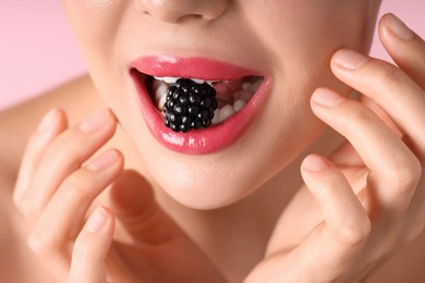 Photo of Woman with beautiful lipstick on her lips and blackberry against pink background, macro view