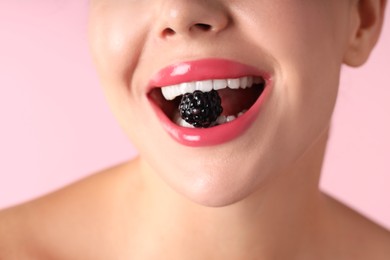 Photo of Woman with beautiful lipstick on her lips and blackberry against pink background, macro view