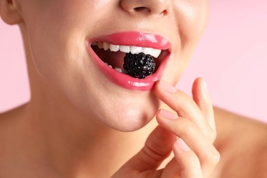 Photo of Woman with beautiful lipstick on her lips and blackberry against pink background, macro view