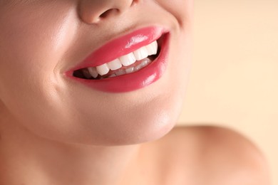 Photo of Woman with beautiful pink lipstick on her lips against beige background, macro view