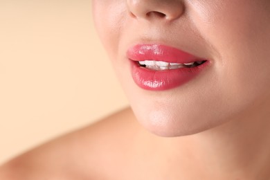 Photo of Woman with beautiful pink lipstick on her lips against beige background, macro view