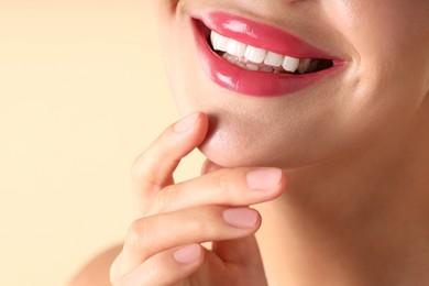 Photo of Woman with beautiful pink lipstick on her lips against beige background, macro view