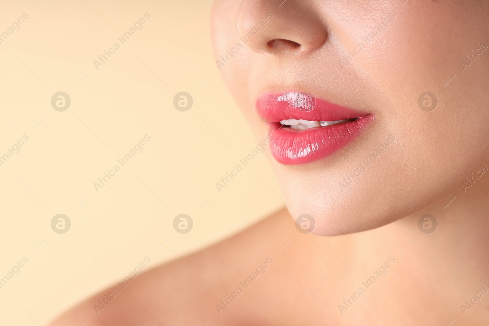 Photo of Woman with beautiful pink lipstick on her lips against beige background, macro view. Space for text