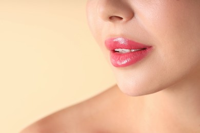 Photo of Woman with beautiful pink lipstick on her lips against beige background, macro view. Space for text