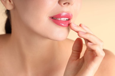 Photo of Woman with beautiful pink lipstick on her lips against beige background, macro view