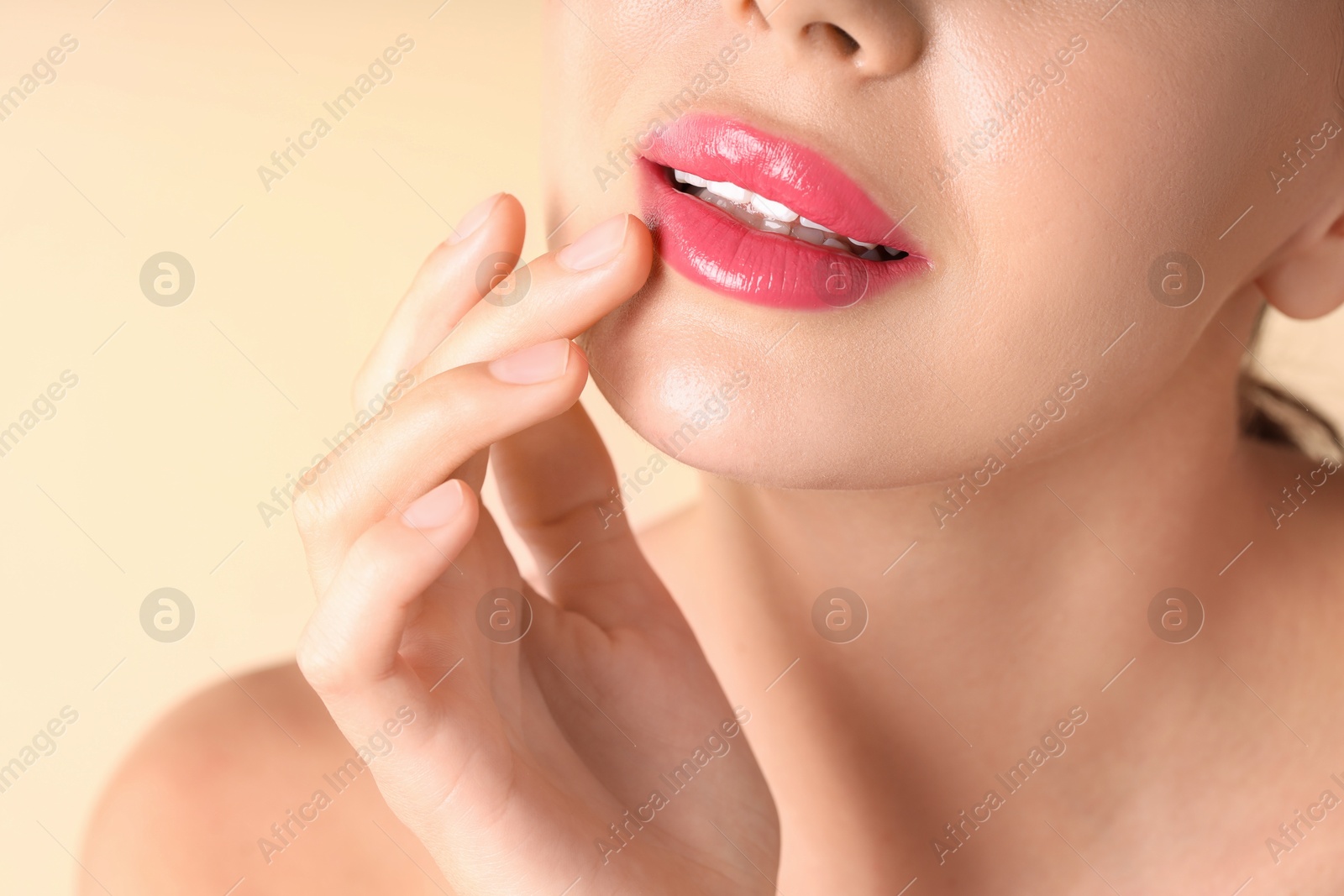 Photo of Woman with beautiful pink lipstick on her lips against beige background, macro view
