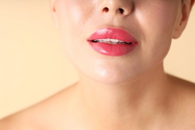 Photo of Woman with beautiful pink lipstick on her lips against beige background, macro view