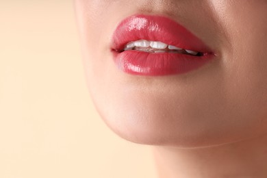 Photo of Woman with beautiful pink lipstick on her lips against beige background, macro view. Space for text