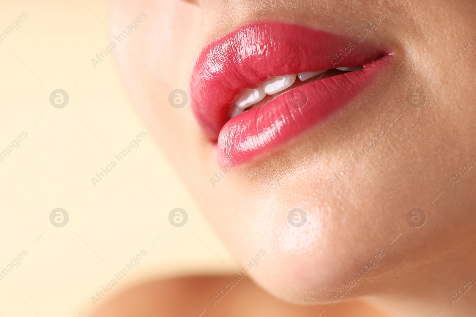 Photo of Woman with beautiful pink lipstick on her lips against beige background, macro view