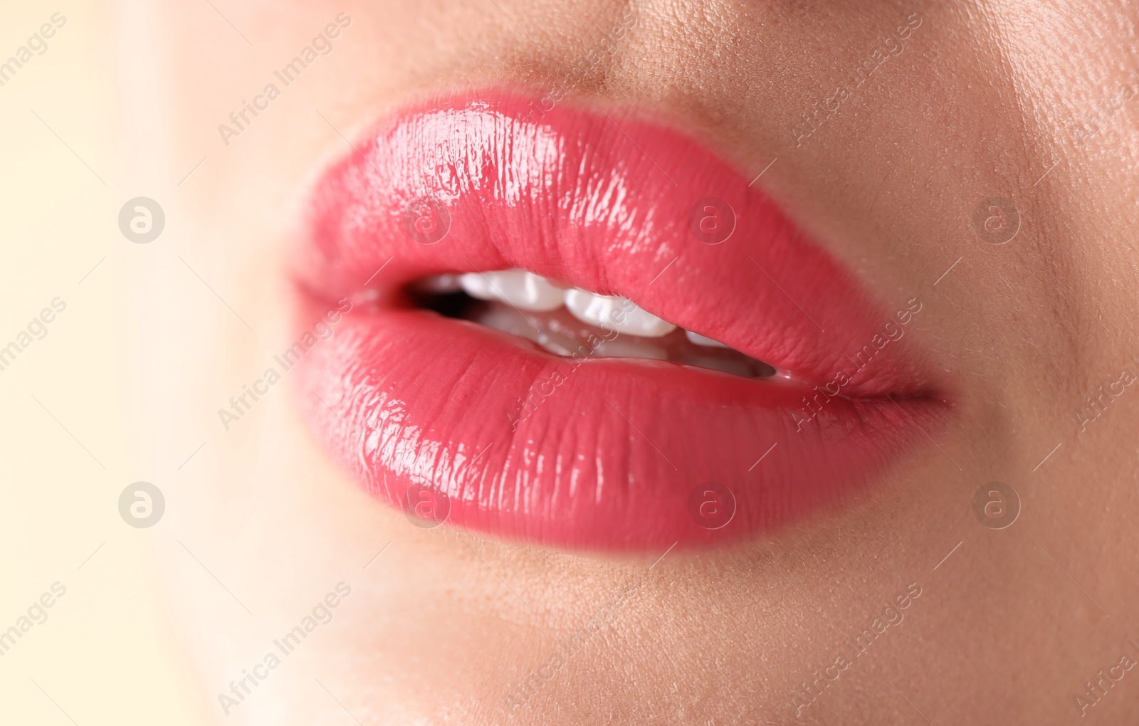 Photo of Woman with beautiful pink lipstick on her lips against beige background, macro view