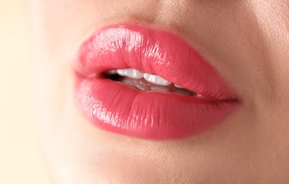 Photo of Woman with beautiful pink lipstick on her lips against beige background, macro view